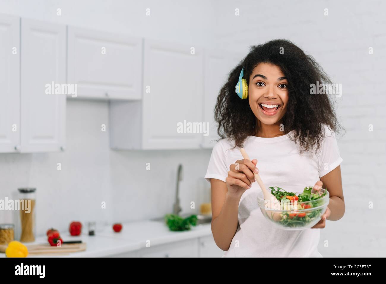 Excitée belle afro-américaine cuisine végétarienne dîner dans la cuisine. Concept de mode de vie sain Banque D'Images