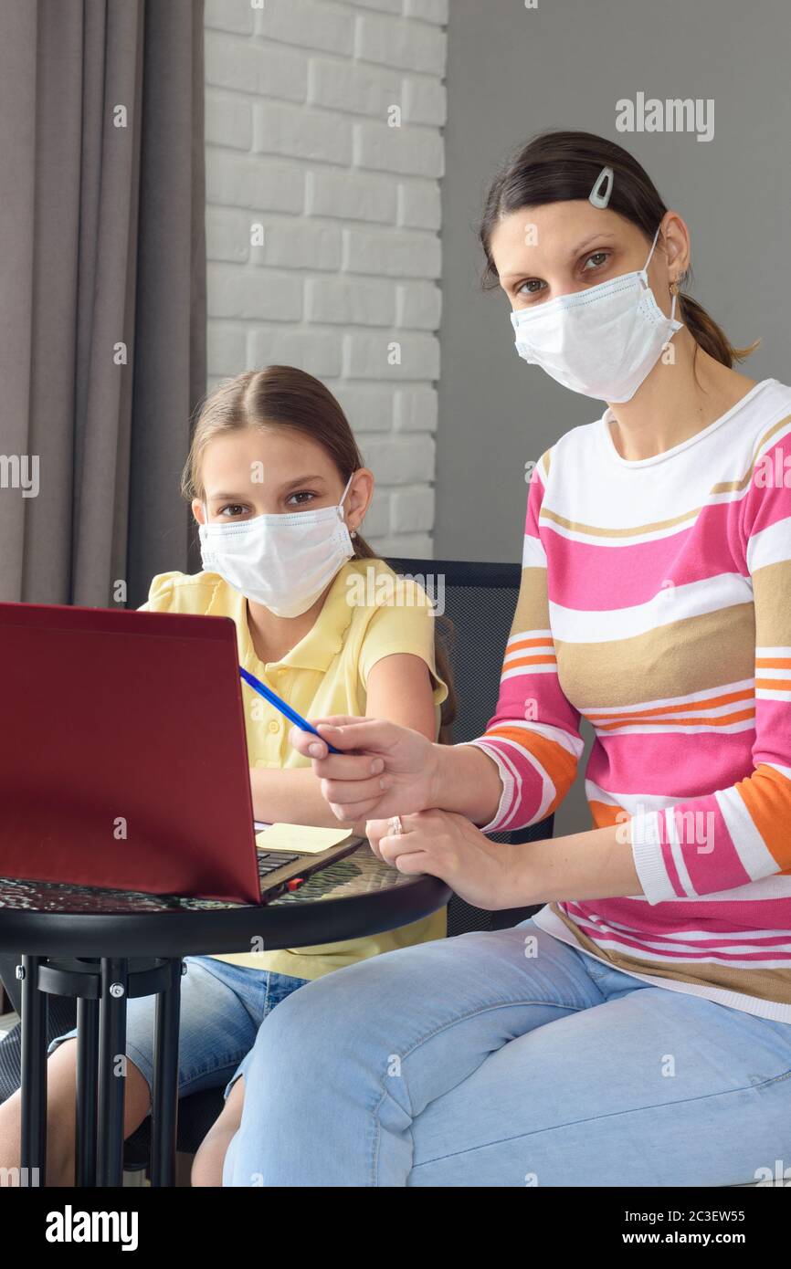 Portrait d'une famille devant un écran d'ordinateur portable dans des masques médicaux Banque D'Images