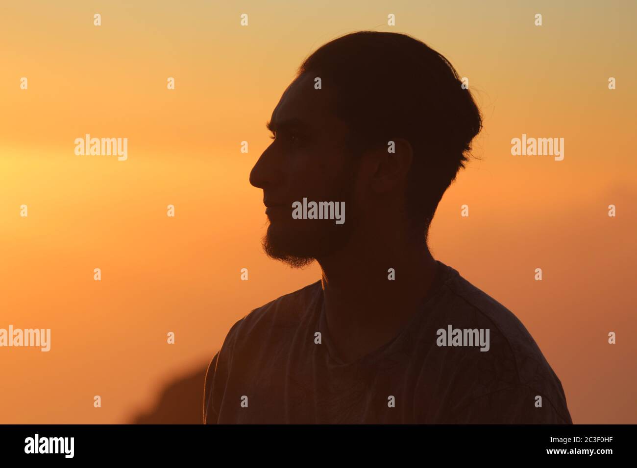 Tenerife, Espagne - 12/19/17: Un homme barbu qui regarde au loin avec un coucher de soleil orange Banque D'Images