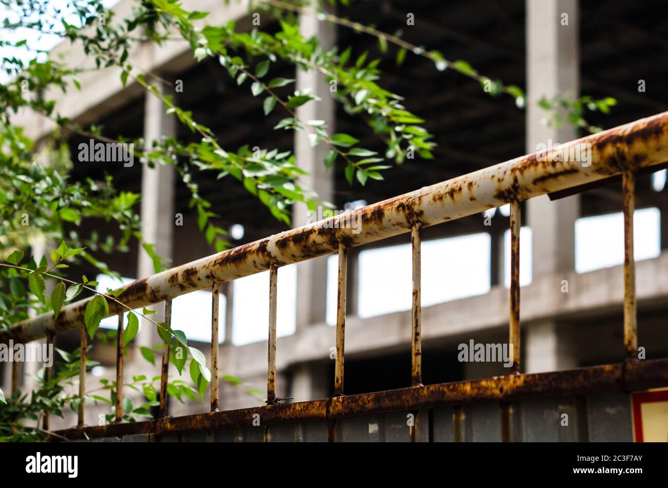 clôture rouillée avec vue sur un bâtiment abandonné Banque D'Images