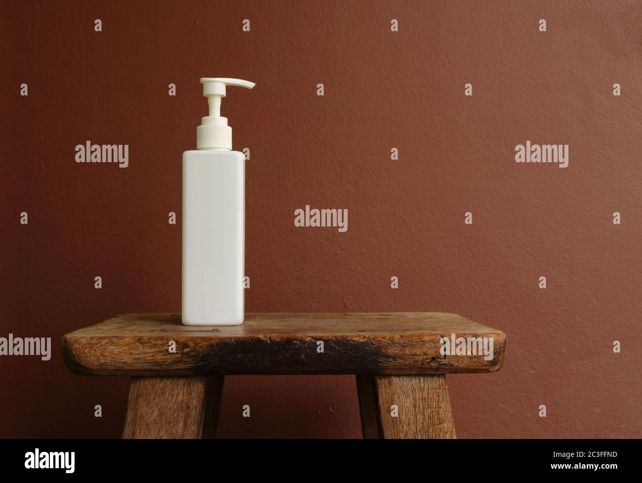 Gros plan bouteille vaporisée blanche placée sur une chaise en bois vintage contre un mur peint en marron Banque D'Images