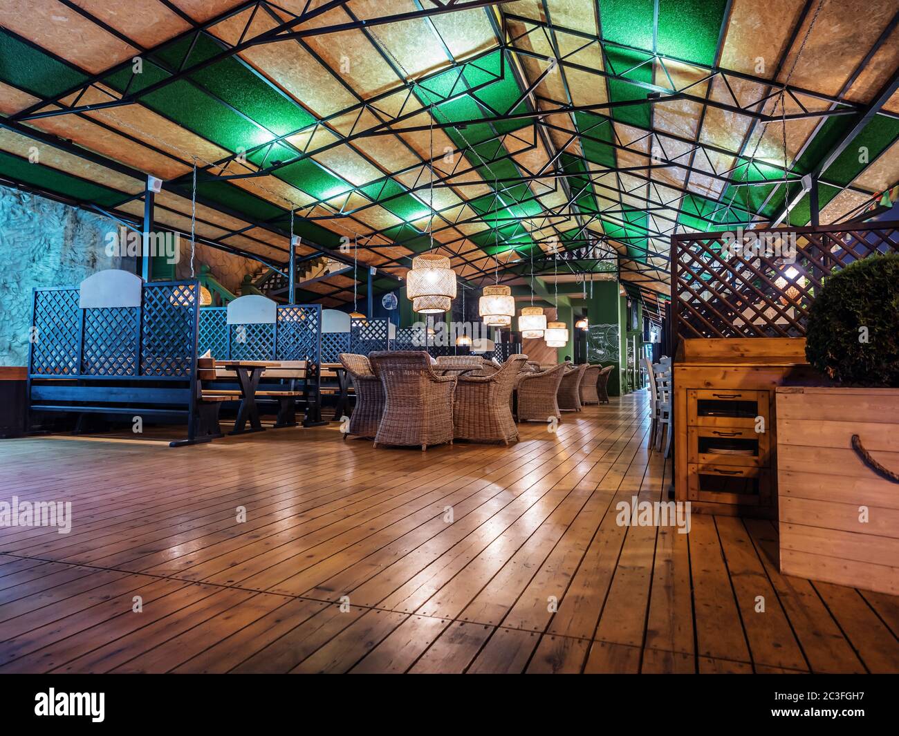 Russie, Sotchi 07.22.2019. Vue en soirée sur un café d'été vide avec parquet, mobilier en osier et lumières sombres Banque D'Images