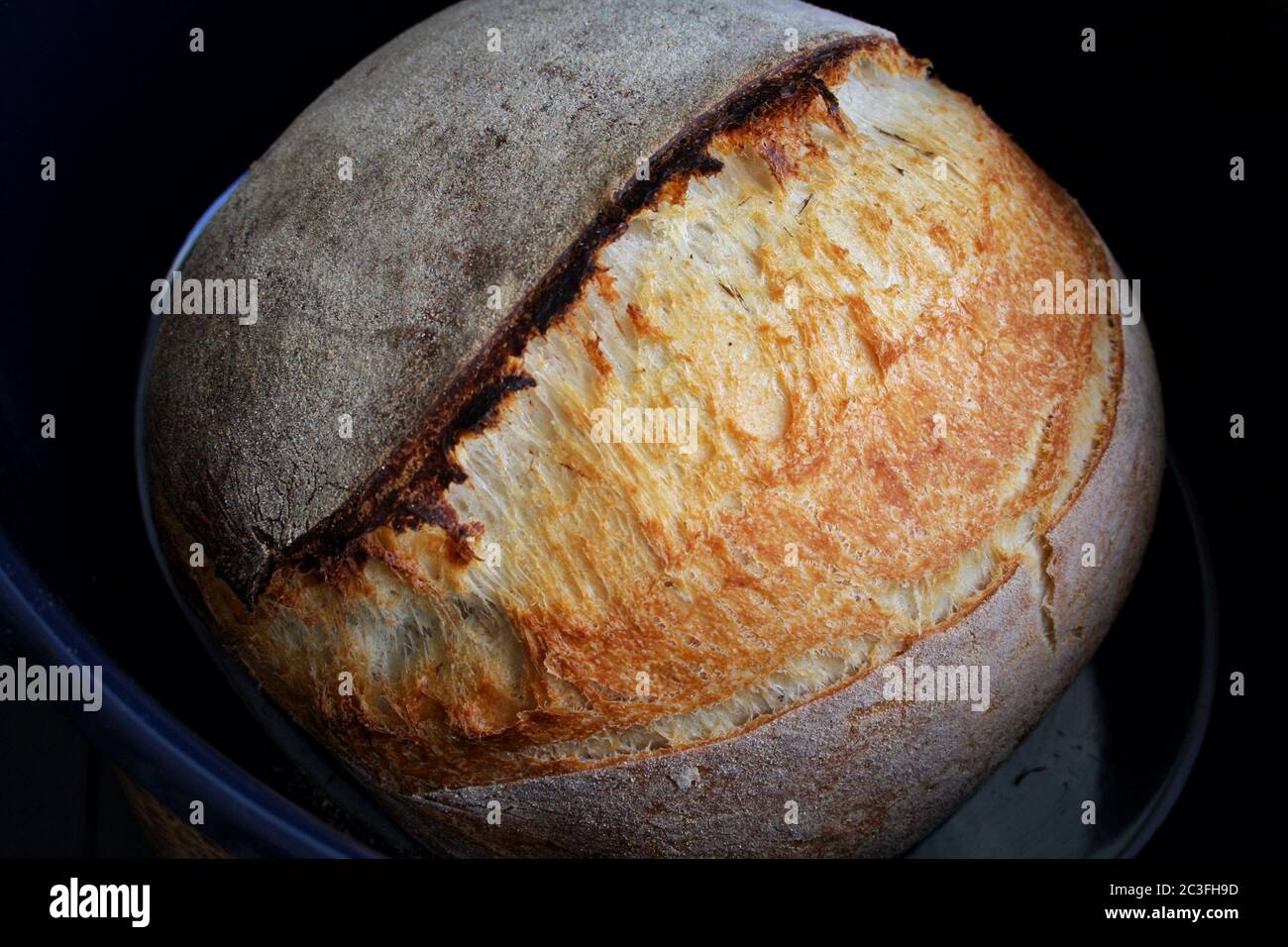 Pain au levain dans un moule bleu sur fond noir. Photographie de pain maison. Illustration de haute qualité Banque D'Images