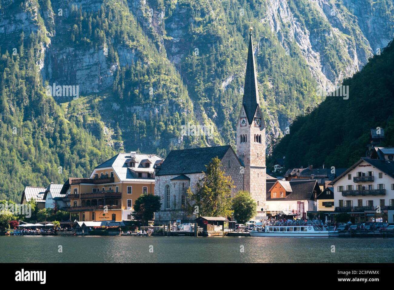 Hallstatt, Autriche - juin 12 2020 : paysage urbain du front de mer de Hallstatt avec église évangélique, bateau de croisière et Seehotel Gruner Baum dans le Salzkammergu Banque D'Images