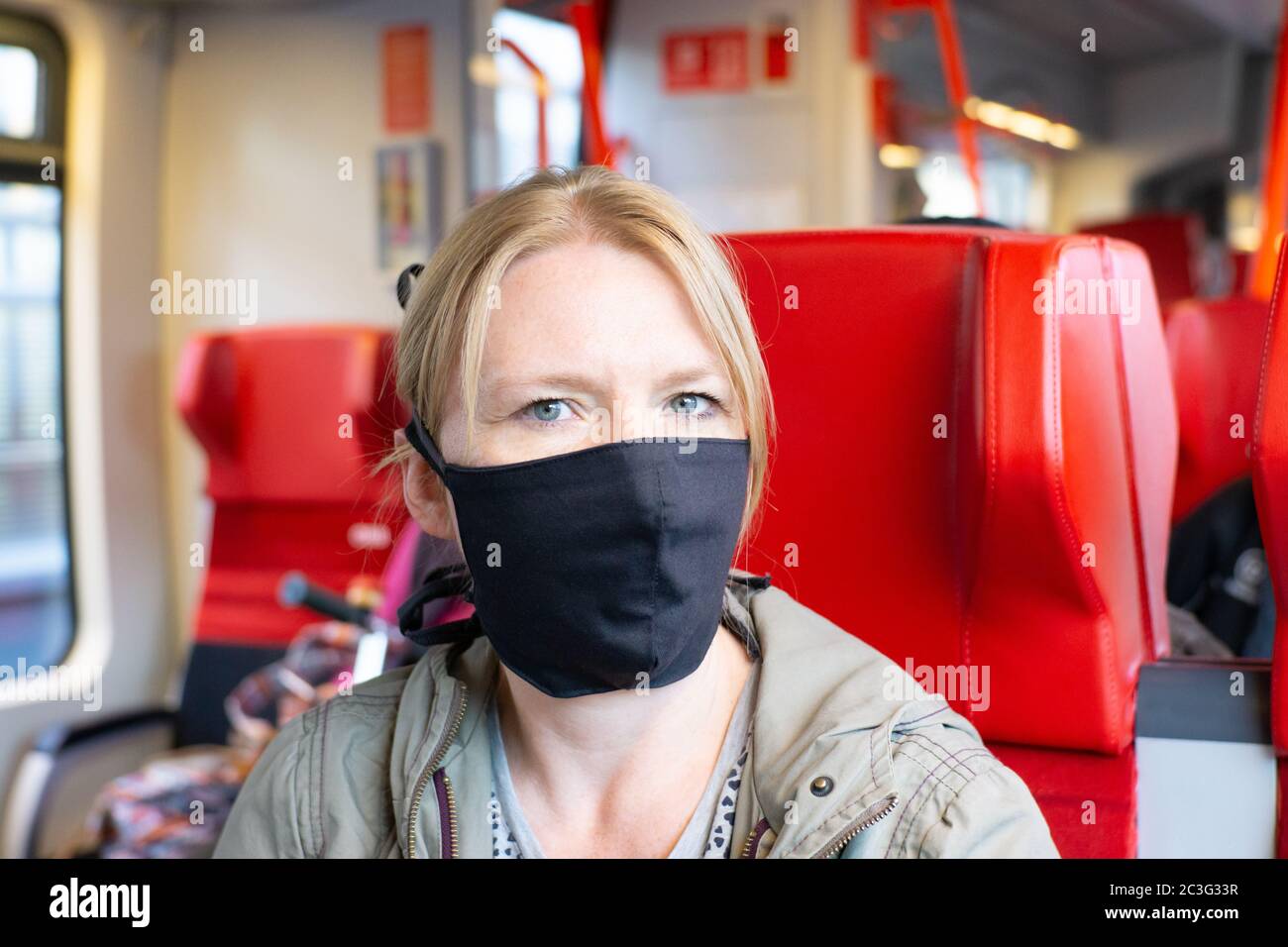 Femme voyageant dans un train ferroviaire portant un masque facial auto-fabriqué. Coronavirus et concept de voyage Banque D'Images