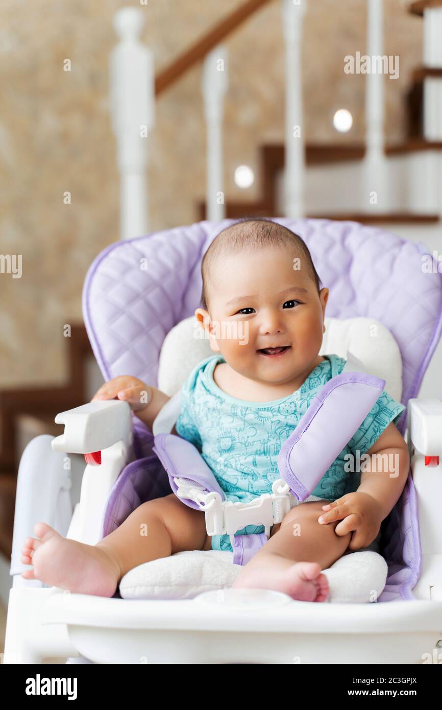 Un Beau Bebe Asiatique De Six Mois Est Assis Dans Un Haut Chaise Et Rire Photo Stock Alamy