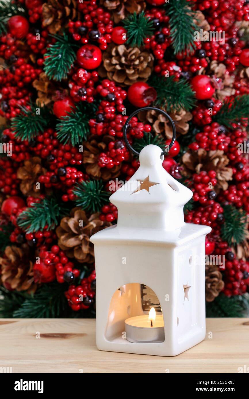 Lanterne en céramique blanche avec une bougie sur fond rouge de Noël en  sapin, baies et cônes. Décoration de fête Photo Stock - Alamy