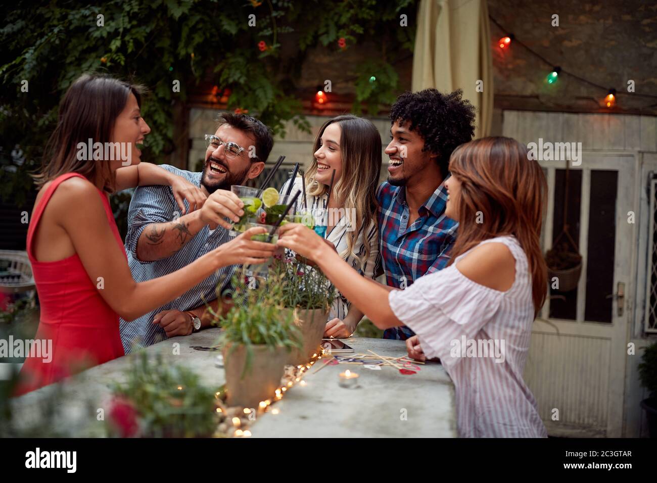 Groupe d'amis célébrant et faisant un toast dans le jardin du café Banque D'Images