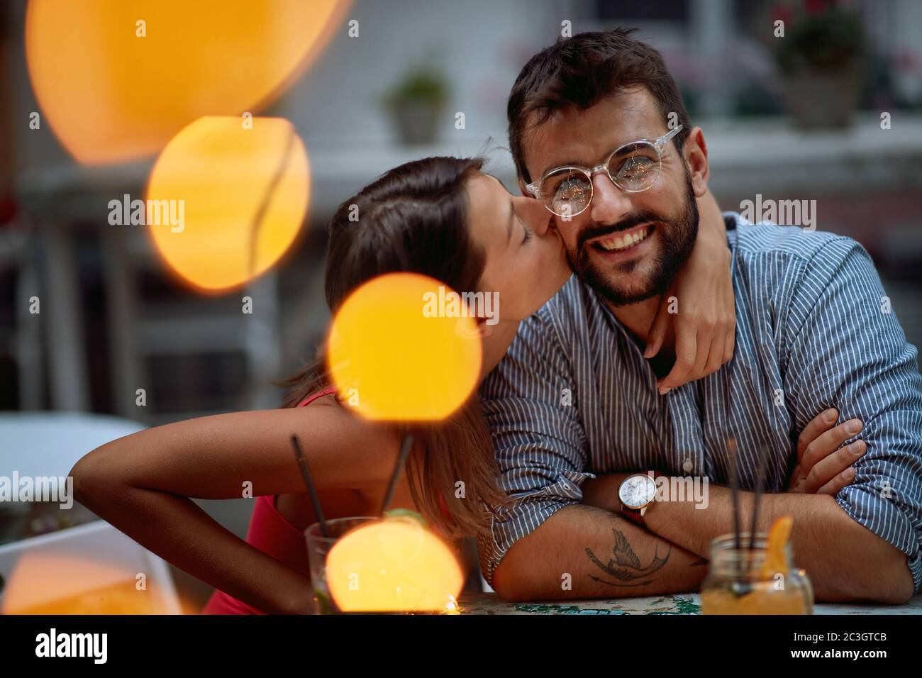 Jeune couple dans un baiser romantique posant à une fête Banque D'Images