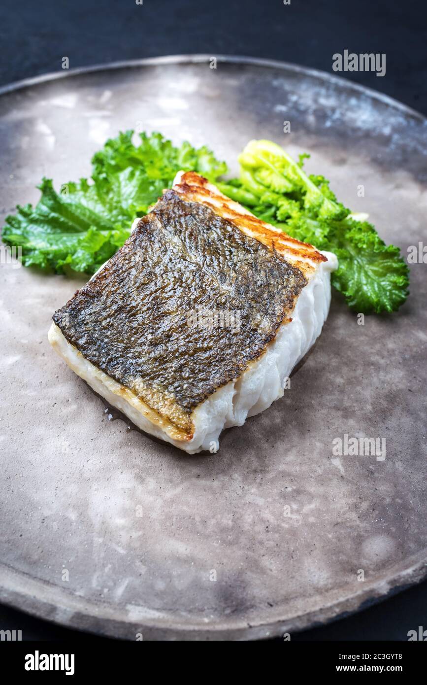 Filet de morue frite de chou frisé européen avec rabe de brocoli rapéni, sur une assiette moderne Banque D'Images