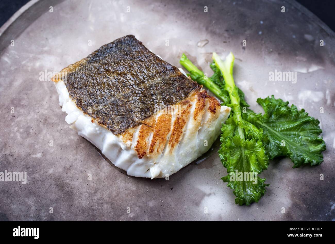 Filet de morue frite de chou frisé européen avec rabe de brocoli rapéni, sur une assiette moderne Banque D'Images