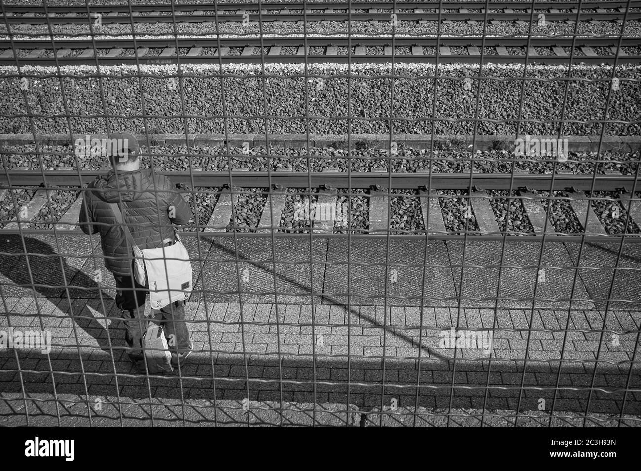 Prise de vue en niveaux de gris d'un homme adulte debout derrière un maillon de chaîne clôture Banque D'Images