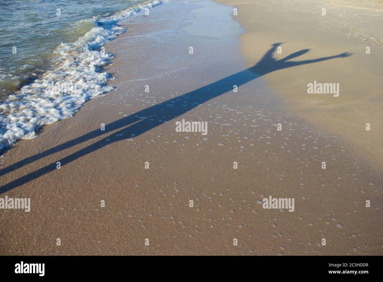 Ombre d'un jeune homme avec ses mains au lever du soleil sur le fond de la mer, l'horizon plage lever du soleil Banque D'Images