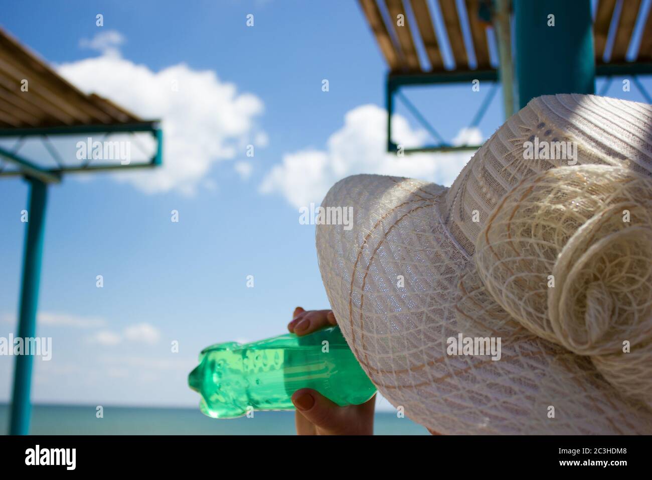 Mer eau de plage repos, femme boit l'eau paysage abri du soleil, nuages ciel Banque D'Images