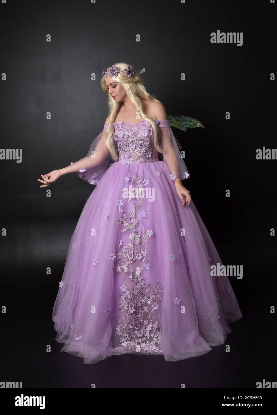 Portrait d'une belle fée blonde portant robe de fantaisie pourpre avec ailes. Posture debout pleine longueur, isolée sur un arrière-plan de studio. Banque D'Images