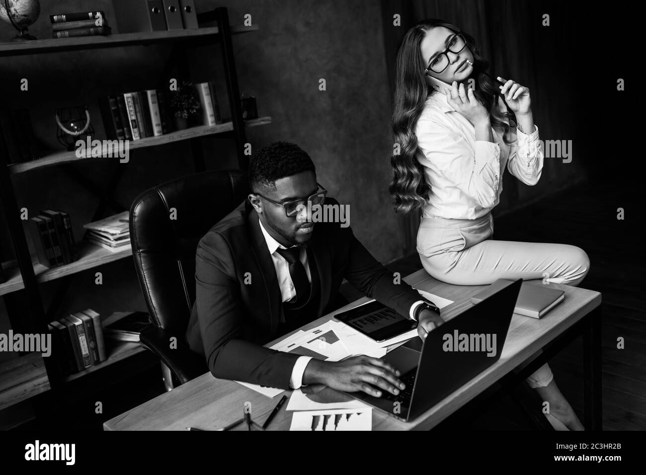 Femme d'affaires parlant au téléphone et interférant avec le travail d'un collègue Banque D'Images