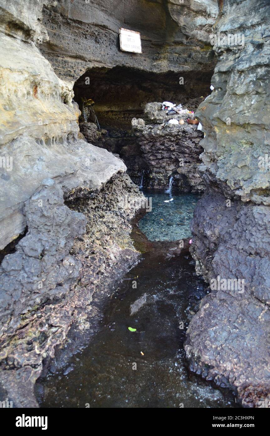 Source sacrée en roche au temple hindou Tanah Lot, Bali, Indonésie. L'eau est utilisée pendant les cérémonies. Banque D'Images