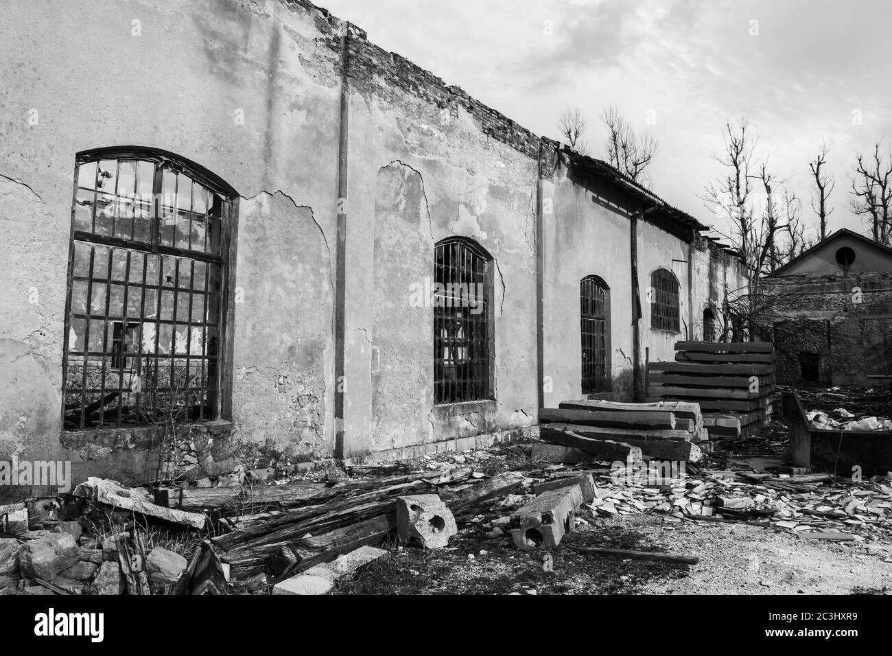 Cliché en échelle de gris d'un bâtiment abandonné avec des murs cassés et fenêtres dans des nuages sombres Banque D'Images