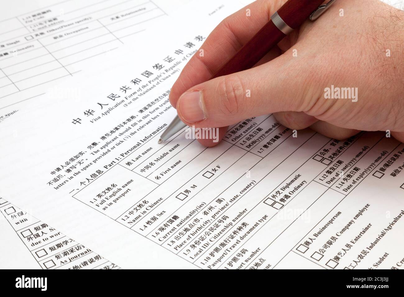 Un homme tenant un stylo à bille pour remplir un formulaire de demande de visa pour la Chine. Banque D'Images