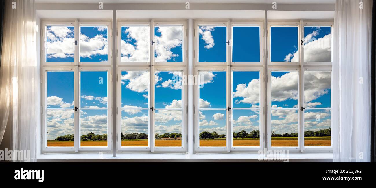 Vue sur fond vert, nature et bleu du ciel à travers le concept de fenêtre ancienne. Panneau de rideau blanc vintage avec cadre, verres transparents, poignées et seuil. Banque D'Images
