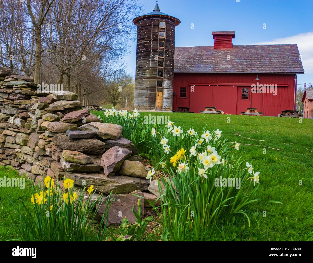 Scène de ferme du Vermont avec un mur en pierre un silo rond historique restauré et une grange rouge au printemps Banque D'Images