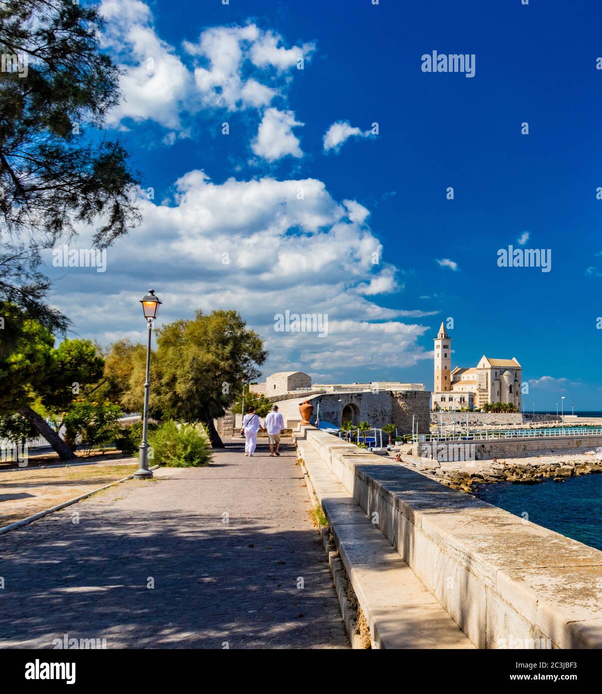 Deux amateurs marchent, main dans le parc municipal de Trani, avec vue sur la mer et la basilique de Saint-Nicolas Pilgrim dans le bac Banque D'Images