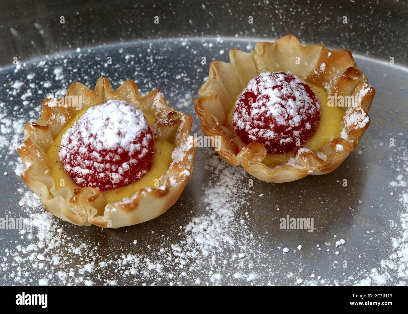 Tarte aux framboises avec crème et sucre en poudre dans une tasse à pâtisserie Banque D'Images
