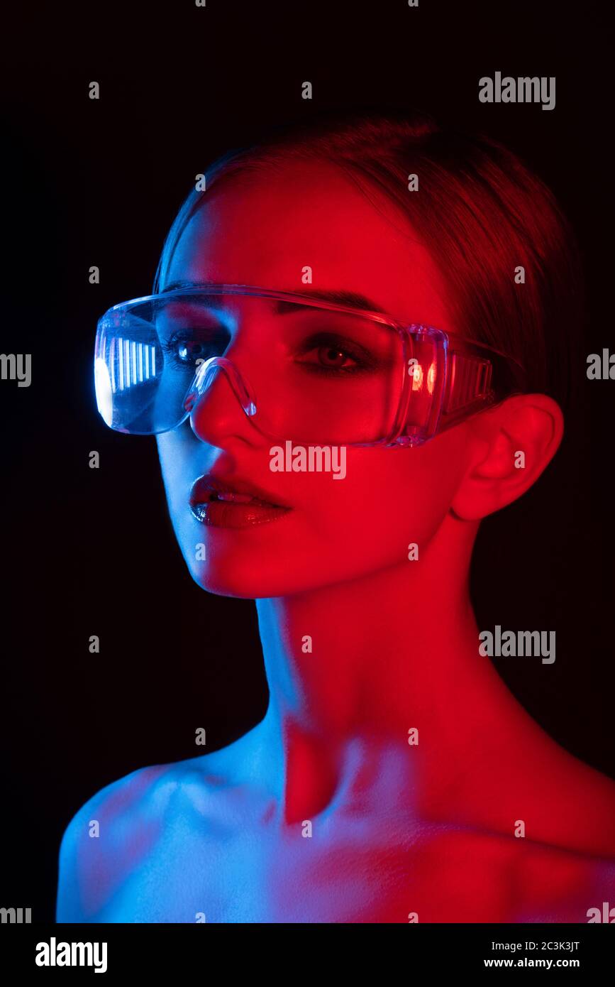 portrait de fille en style disco avec lumière bleue et rouge, fille en grandes lunettes transparentes avec de grands yeux et peau lisse, Banque D'Images