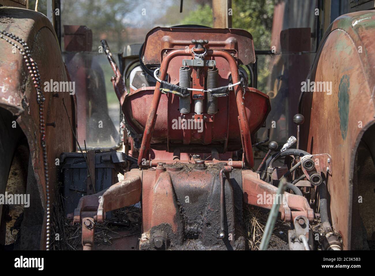 Vieux tracteur rouge rouillé avec arbres flous en arrière-plan Banque D'Images