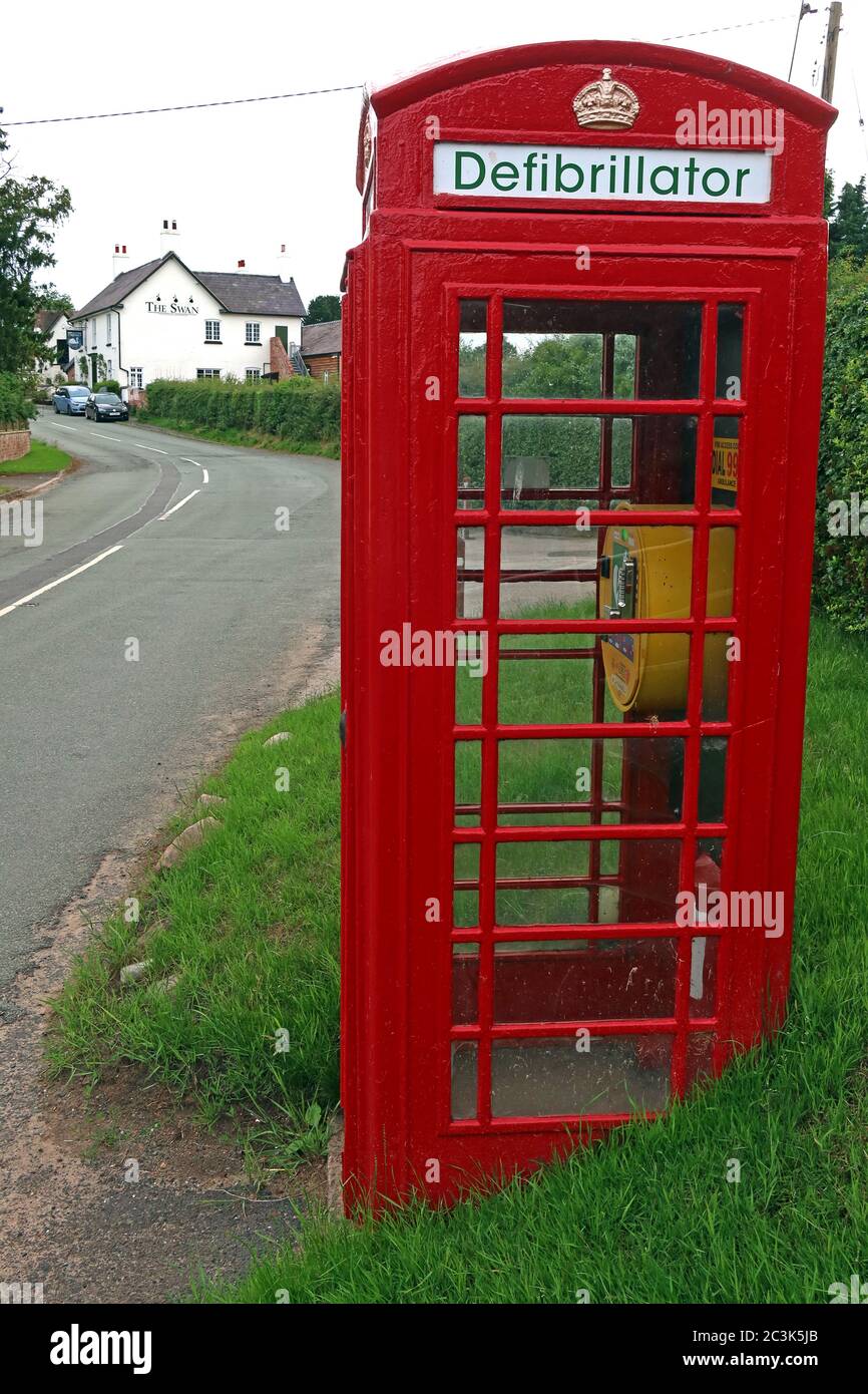 Défibrillateur dans un coffret téléphonique britannique rouge, Marbury Village, Cheshire, Angleterre, Royaume-Uni, DAE, secourisme cardiaque - sauver des vies Banque D'Images