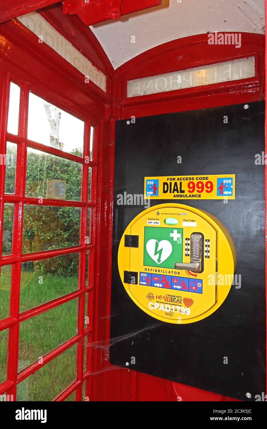 Défibrillateur dans un coffret téléphonique britannique rouge, Marbury Village, Cheshire, Angleterre, Royaume-Uni, DAE, secourisme cardiaque - sauver des vies Banque D'Images