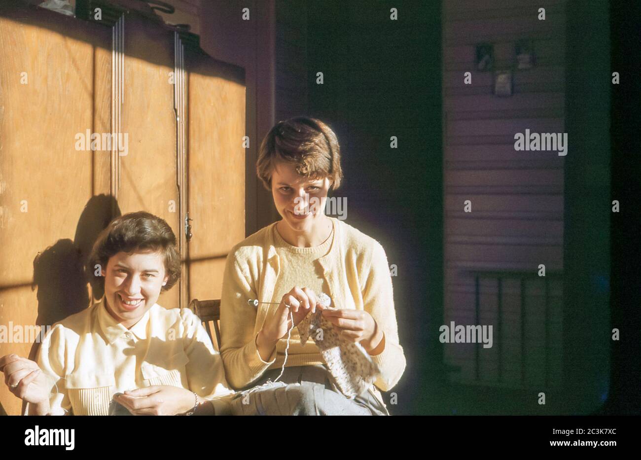 Castle Hill, Sydney Australie hiver 1958 : deux jeunes femmes australiennes s'assoient sur une véranda ouverte sous le soleil de l'après-midi, tricoter et coudre Banque D'Images