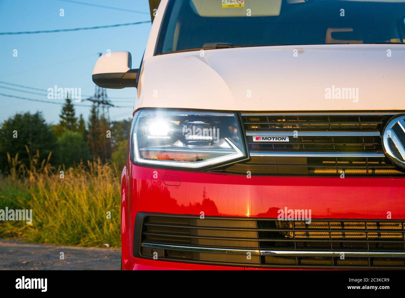 Saint-Pétersbourg, Russie - 22 juillet 2019 : Volkswagen Multivan California Ocean (transporteur T6), de couleur rouge et blanc. Est garé sur la route de campagne. Gros plan des phares À LED Banque D'Images