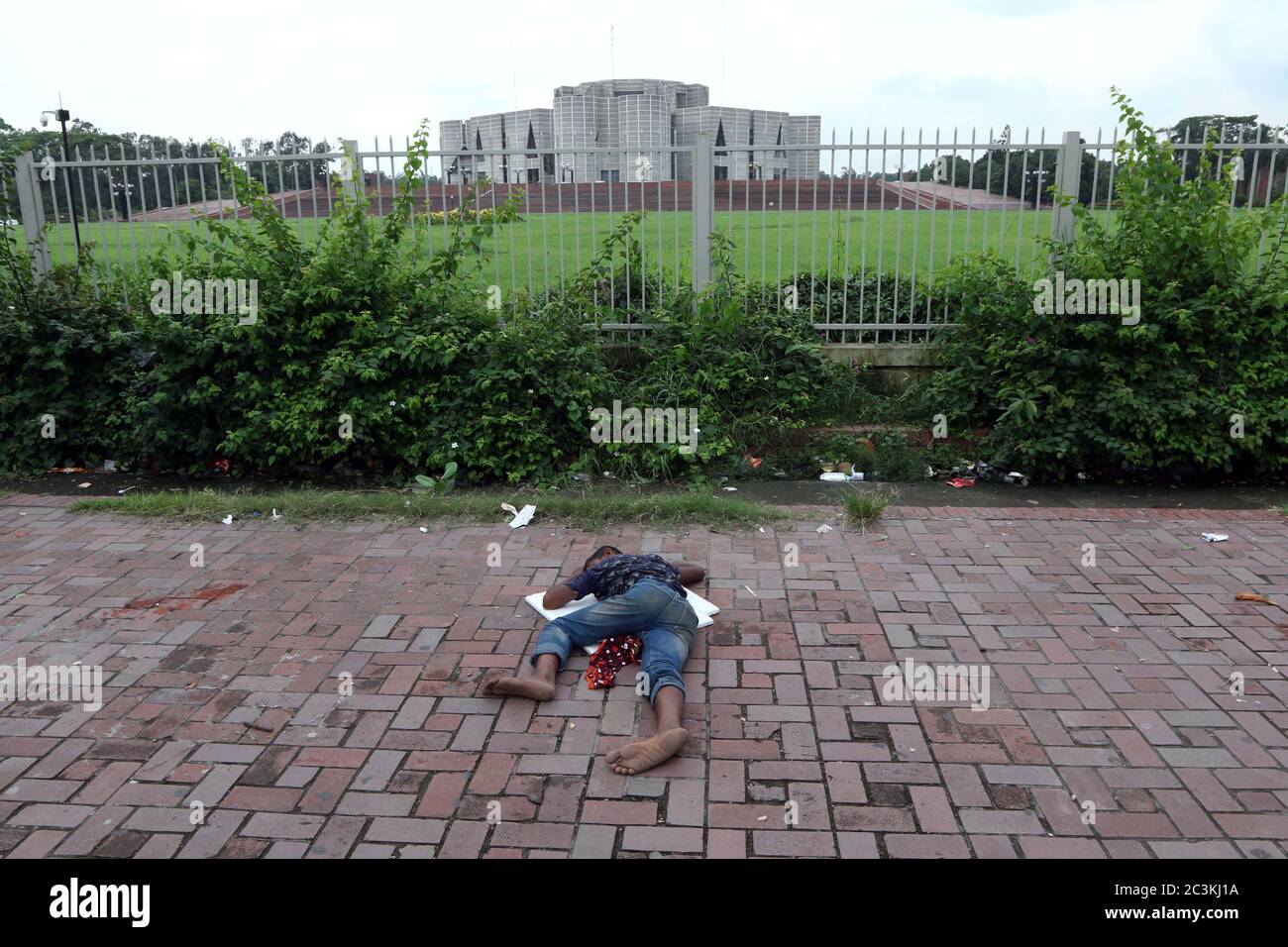 Un enfant bangladais sans abri dort sur la piste de marche près d'un Parlement national du Bangladesh à Dhaka le 20 juin 2020. Banque D'Images