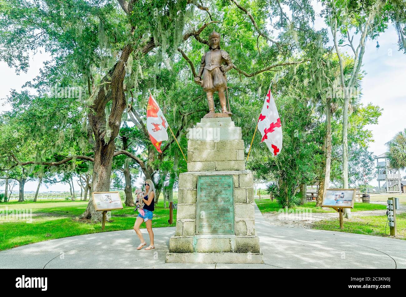 Une femme et son chien marchent devant une statue de bronze de Ponce de Leon à la fontaine de Pence de Leon du Parc archéologique de la jeunesse St. Augustine, Floride. Banque D'Images