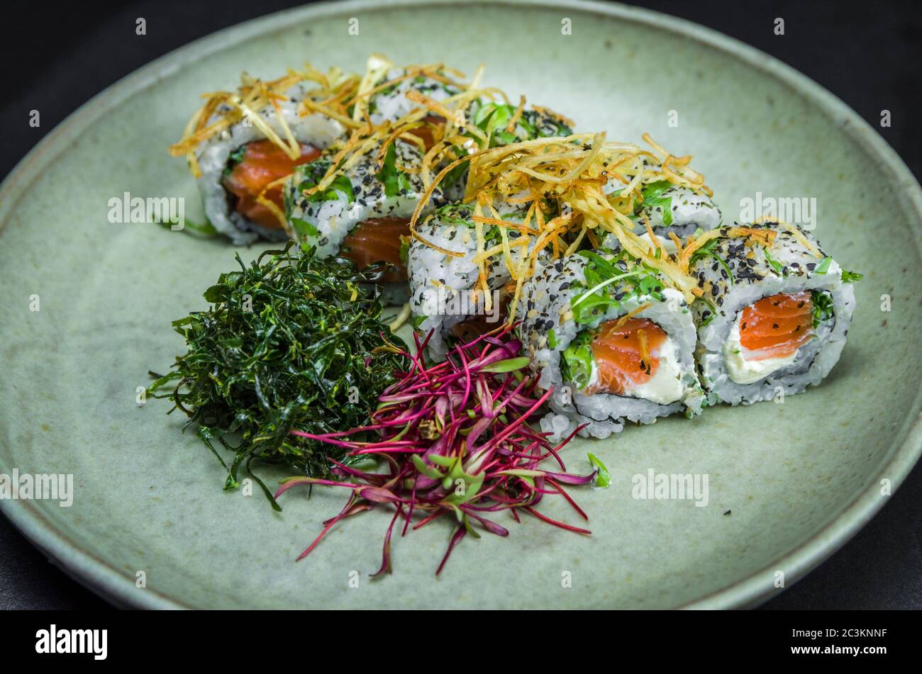 Sushi, cuisine japonaise traditionnelle. Délicieux uramaki sur plaque décorée, fond noir. Banque D'Images