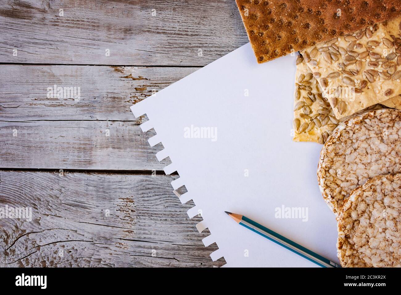 alimentation utile, pain de croustillant, flocons, sarrasin, biscuits avec tournesol sur fond texturé. Une feuille de papier crayon pour écrire votre texte. Banque D'Images