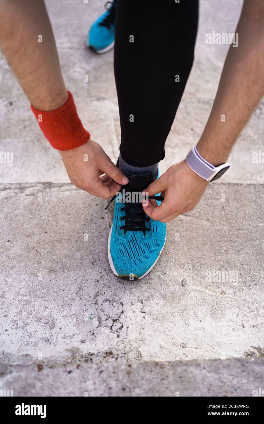 Le coureur attache ses chaussures de course. Homme chaussure, ses sneakers  bleues avec montre intelligente sur son poignet Photo Stock - Alamy