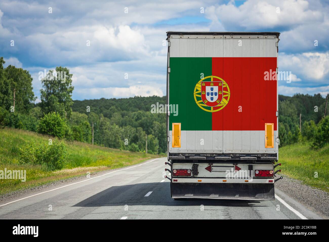 Un camion avec le drapeau national du Portugal représenté sur la porte arrière transporte des marchandises vers un autre pays le long de la route. Concept d'exportation-importation,tra Banque D'Images