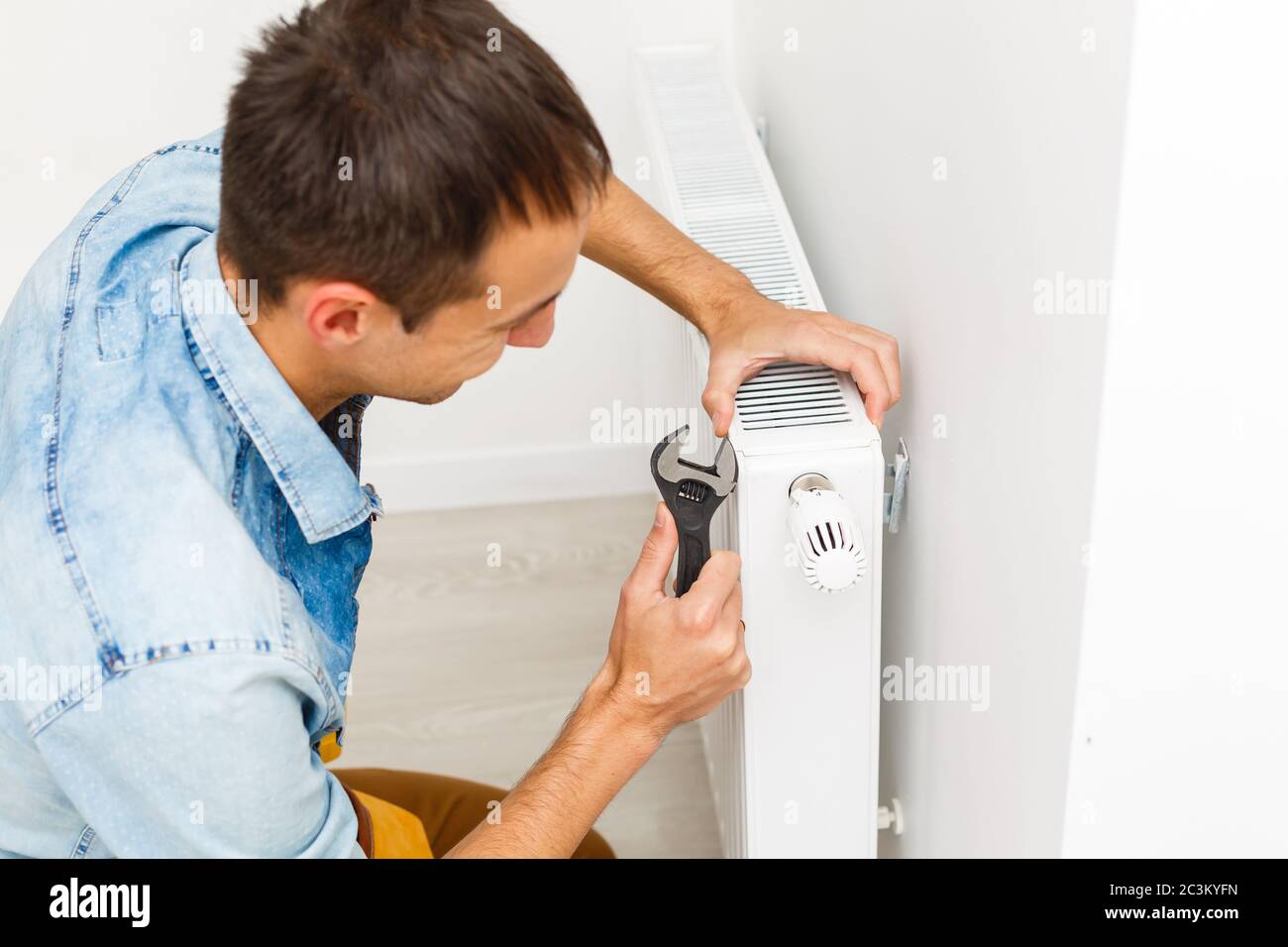 Un homme répare la batterie du radiateur dans la pièce. Travaux de  réparation d'entretien rénovation de l'appartement. Restauration du  chauffage. Clé à main Photo Stock - Alamy