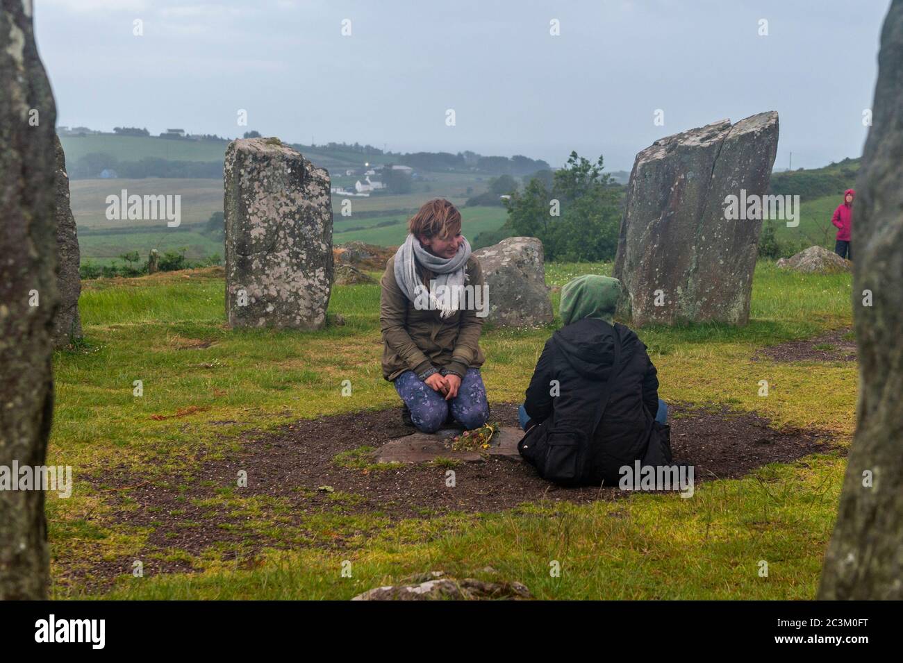 Glandore, West Cork, Irlande. 21 juin 2020. Le soleil se lève derrière la couverture nuageuse au-dessus du cercle de pierres de Drombeg, marquant le début du solstice d'été, le plus long jour de l'année. Le cercle de pierre de Drombeg, également connu sous le nom d'autel des Druides, est un cercle de pierre mégalithique. Deux Pagans placent des offrandes à l'intérieur du cercle de pierre. Crédit : AG News/Alay Live News Banque D'Images