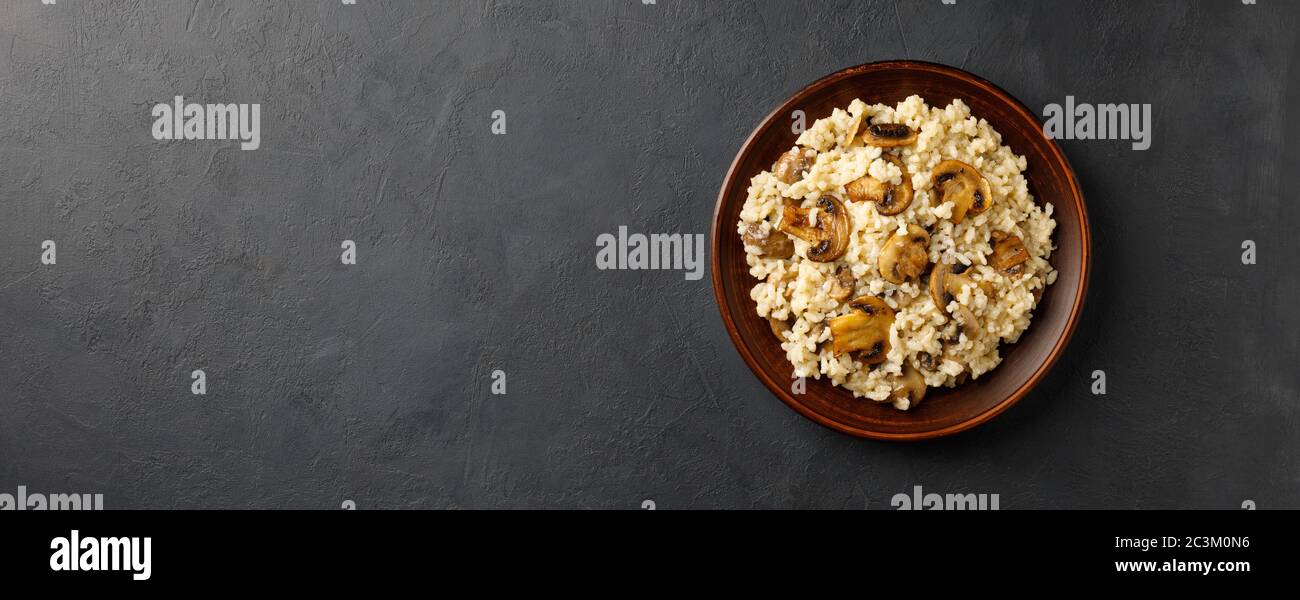 Repas de cuisine italienne traditionnelle - risotto végétarien aux champignons. Fond noir en pierre. Concept de menu de restaurant ou de café. Format de bannière long. Banque D'Images