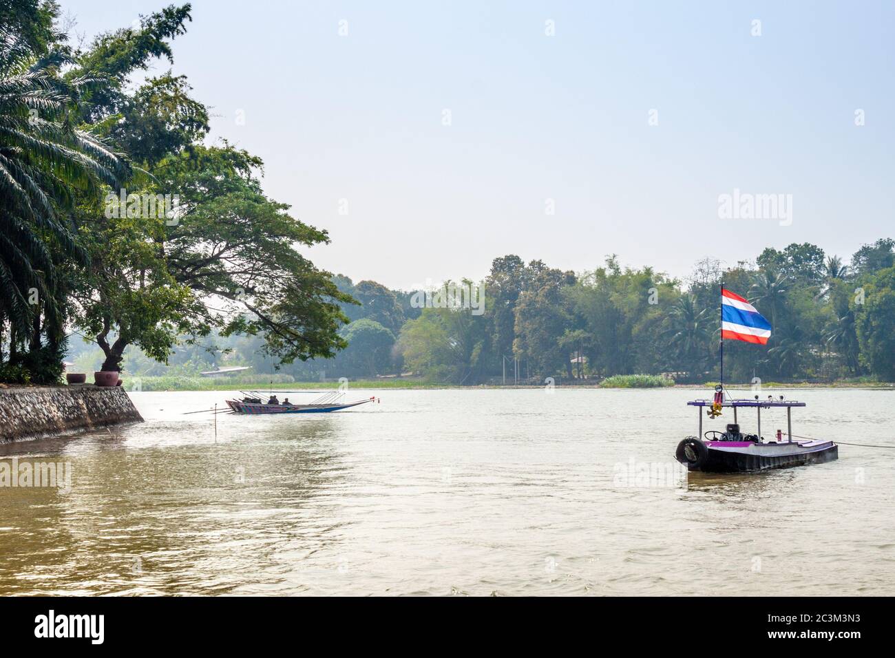 Bateau portant le drapeau de la Thaïlande sur le fleuve Khwae Yai. Banque D'Images