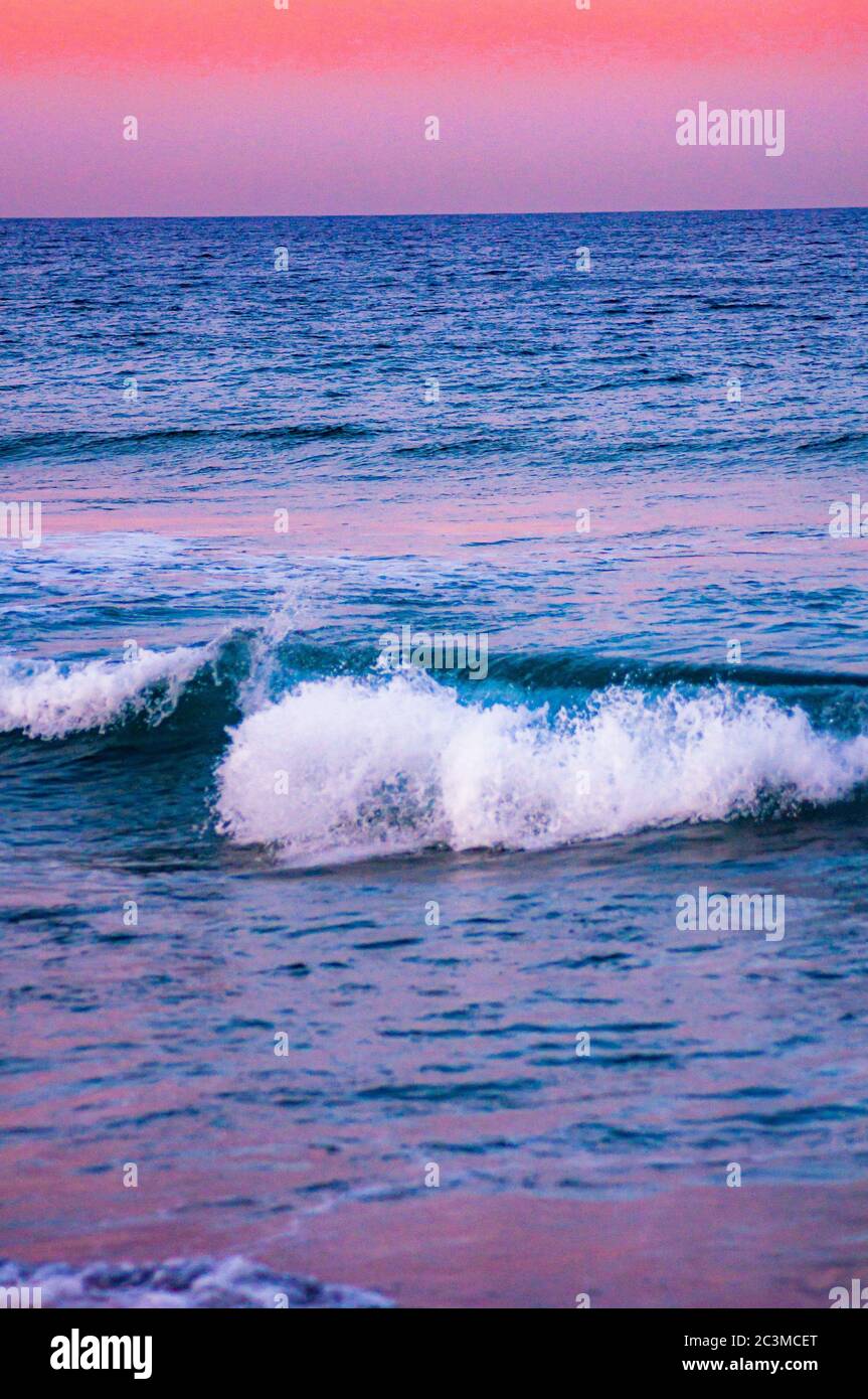 Belle photo des vagues de l'océan sous-luisant le ciel rose - super pour  les fonds d'écran Photo Stock - Alamy