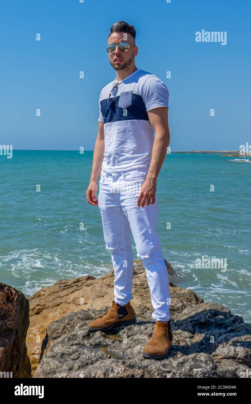 Jeune homme en pantalon blanc et style moderne posé sur la plage de la mer  Méditerranée à Burriana. Mode Photo Stock - Alamy