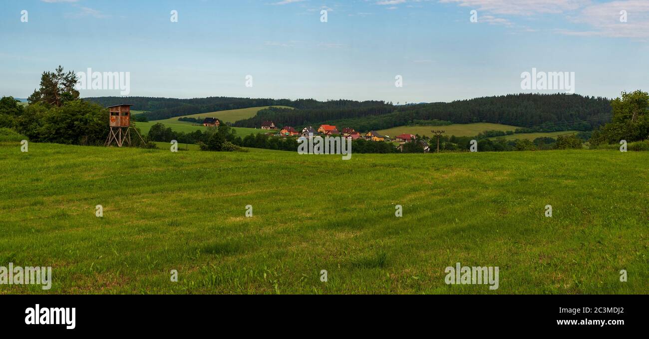 Magnifique paysage vallonné au-dessus du village de Valaske Prikazy en République tchèque avec des prairies, un petit village sur la vallée, des collines et un stand de chasse Banque D'Images