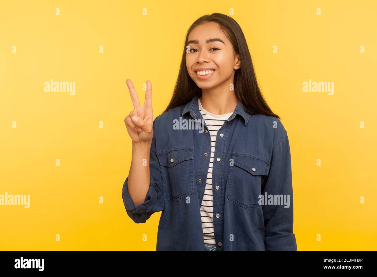 Je gagne ! Portrait de joyeuse fille heureuse en chemise denim montrant le geste de victoire, les doigts doubles, la paix ou le signe v, heureux au sujet de la réussite, point de vue optimiste. ind Banque D'Images