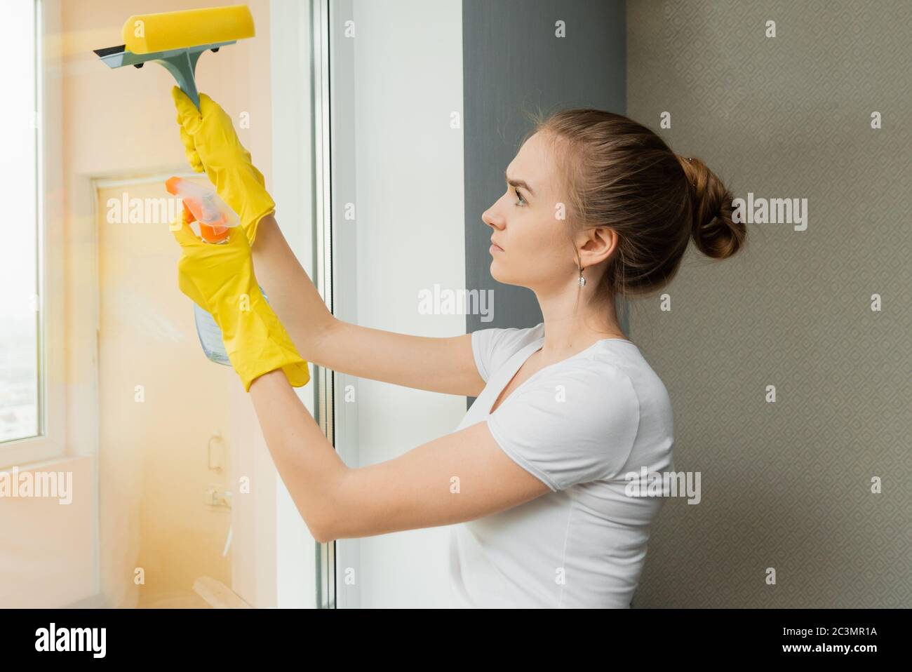 Une femme de ménage mignonne femme de travail de nettoyage essuie des  fenêtres en plastique dans une maison. La vue de l'extérieur Photo Stock -  Alamy