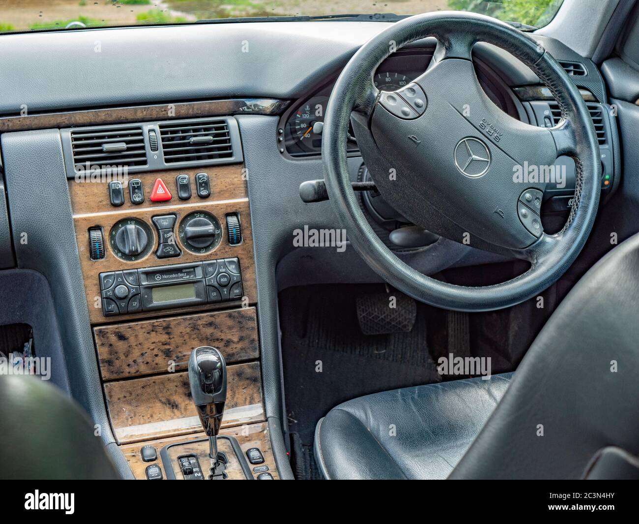 L'espace intérieur avant conducteur d'une conduite à droite, immatriculée au Royaume-Uni, Mercedes classe E W210 - une voiture automatique bien utilisée de 2000. Banque D'Images