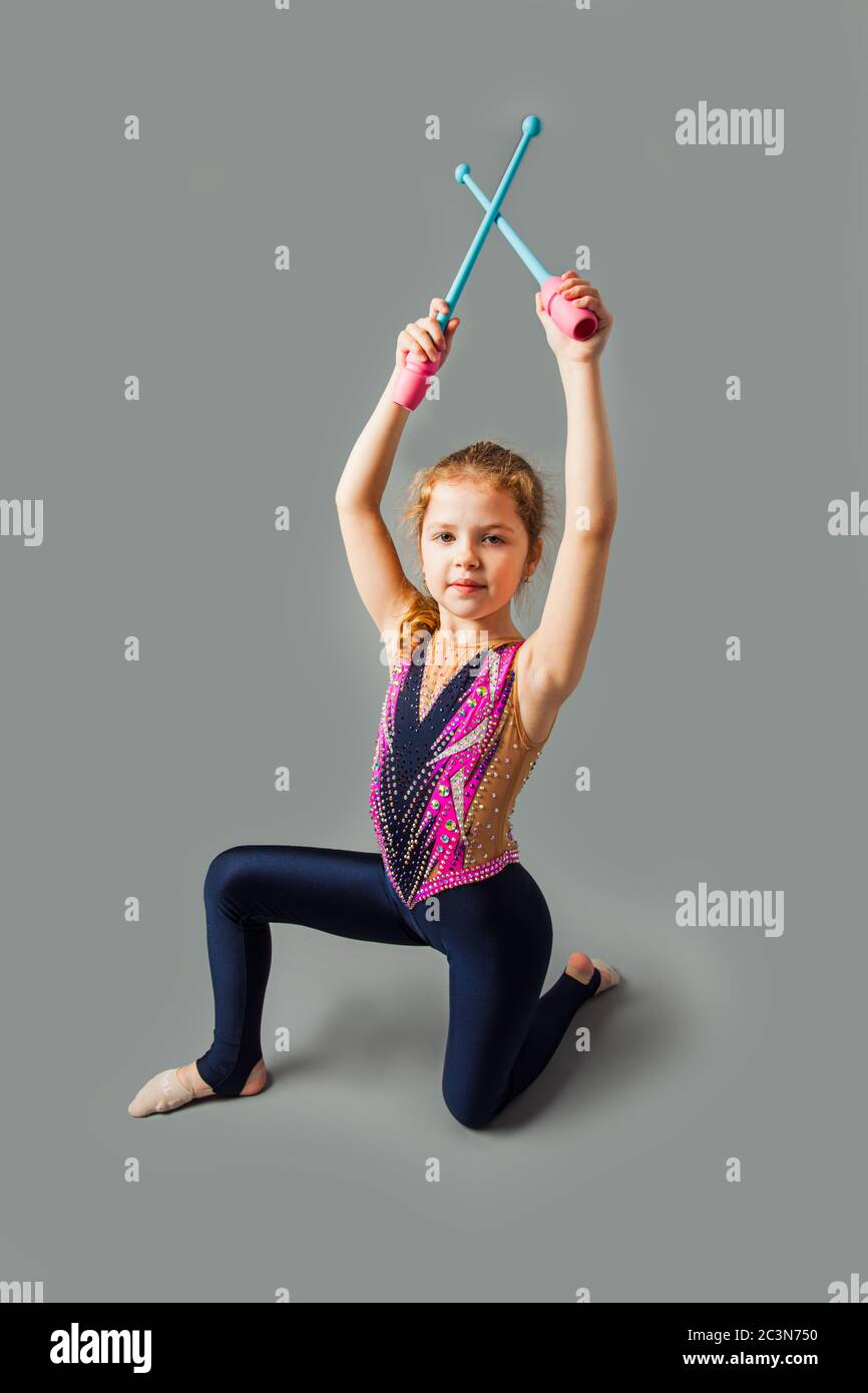 Bonne fillette de gymnastique dans un costume, tenant des bâtons Banque D'Images